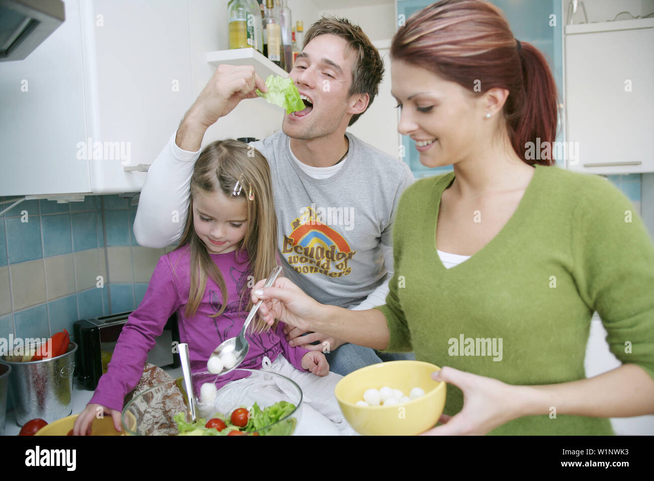 Jeune famille préparer une salade dans une cuisine domestique, Munich, Allemagne Banque D'Images