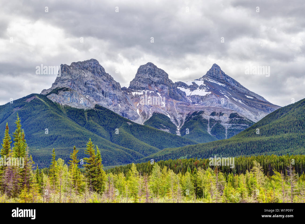 Canmore célèbre Trois Sœurs des pics de montagne dans le sud de la gamme Banff Canadian Rockies nuageux sur un matin de printemps. Le trio des pics sont na Banque D'Images