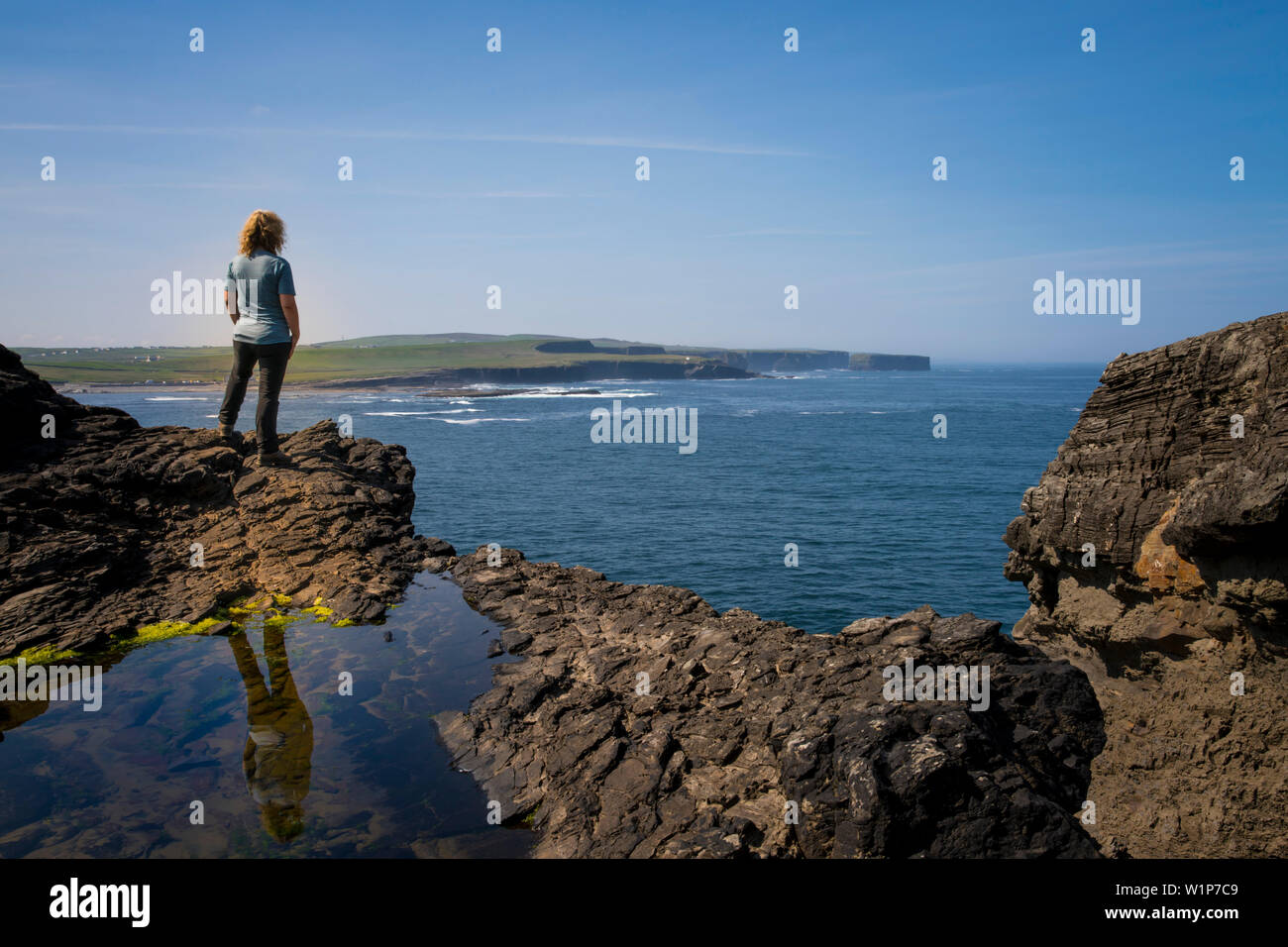 Au lookout point près de Georges tête sur les falaises de Kilkee, une femme se dresse sur les rochers et donne sur la côte, Byrnes Cove, comté, Kilkee Banque D'Images