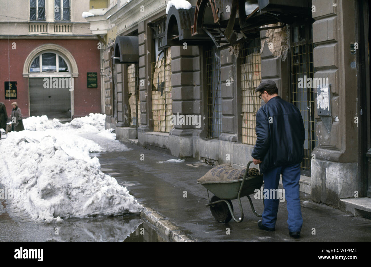 28 mars 1993 pendant le siège de Sarajevo : un homme pousse une brouette transportant un sac de HCR ou du maïs grain séché sur Jugoslovenske Narodne Armije Zelenih beretki (rebaptisée rue après la guerre). Banque D'Images