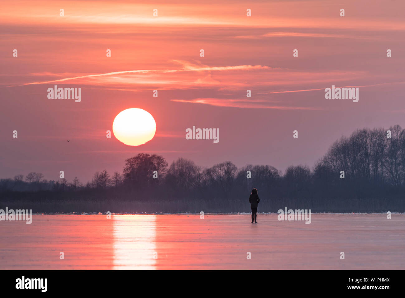 Coucher de soleil rouge en hiver sur un lac gelé en Allemagne Banque D'Images