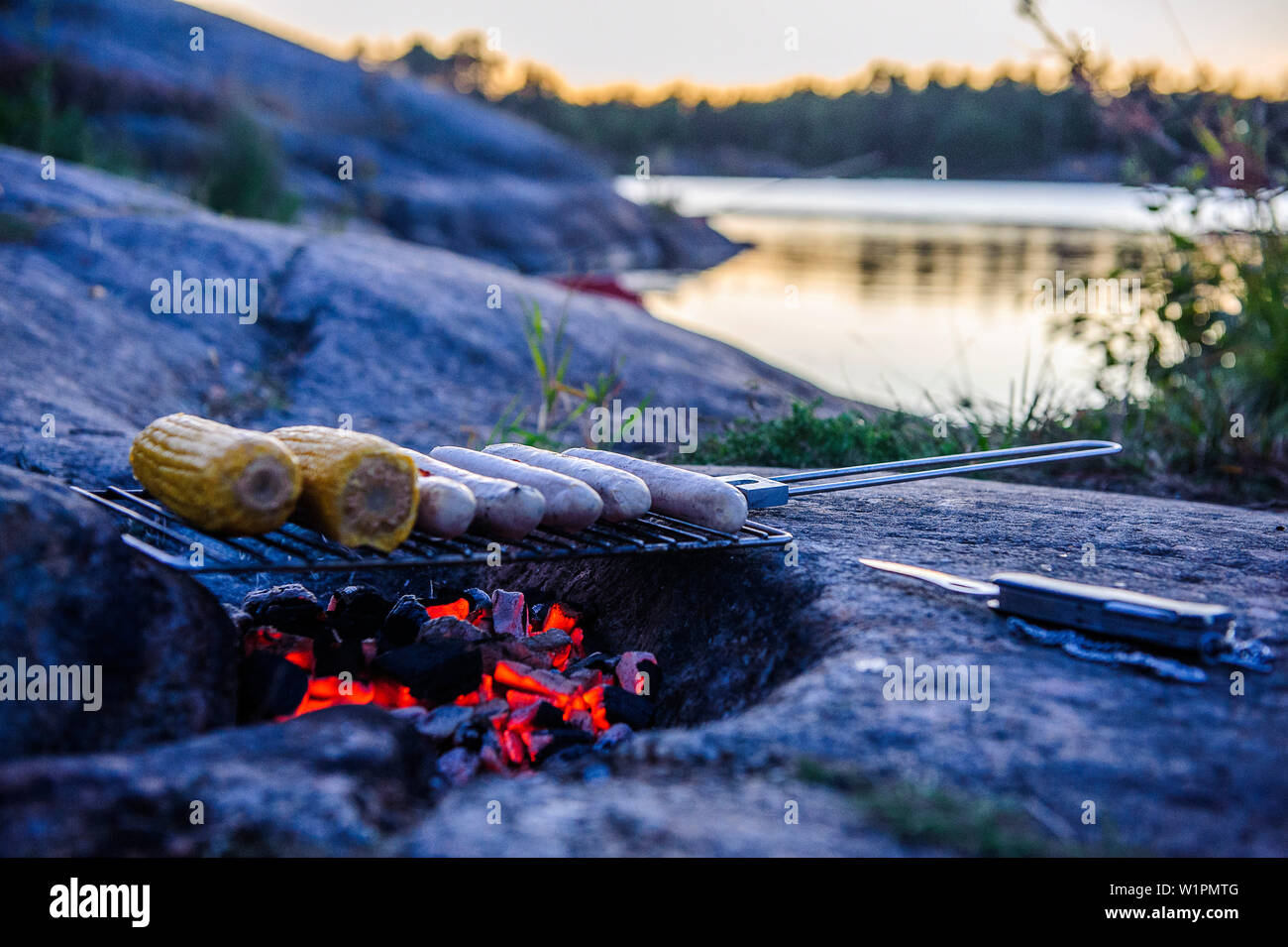 Par le feu de camp, barbecue près de Kaellandsoe Lackoe château sur le Lac Vänern, Suède Banque D'Images