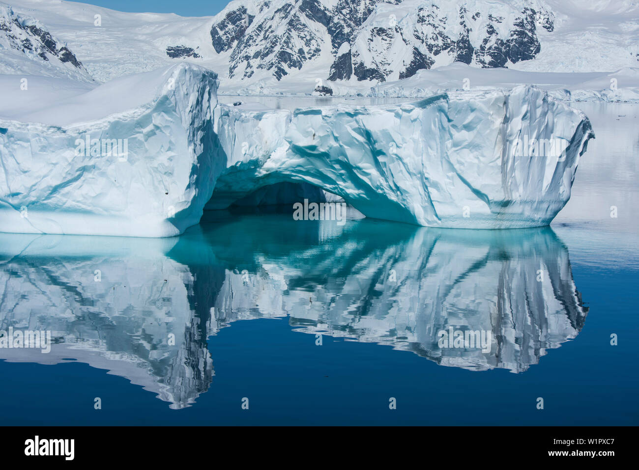 Un moment rare, windstill crée une image inversée d'une formation de glace dotée d'un arc surbaissé, Wilhelmina Bay, péninsule Antarctique, l'Antarctique Banque D'Images