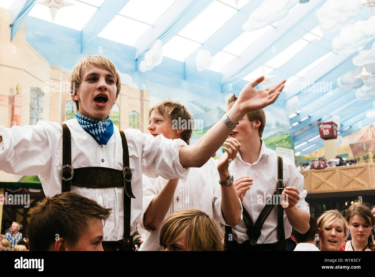 Les jeunes hommes en pantalon de cuir debout sur les bancs de la bière Oktoberfest célébrer dans la tente à bière Banque D'Images