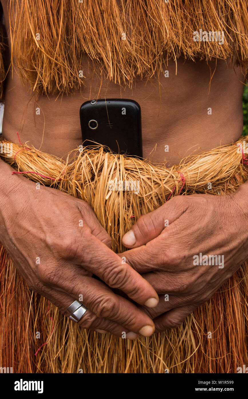Un membre de la gens Witoto (aussi) Guarayu) porte un cell-phone rempliés dans la taille de ses vêtements traditionnels faits de fibres végétales, Pebas (également P Banque D'Images
