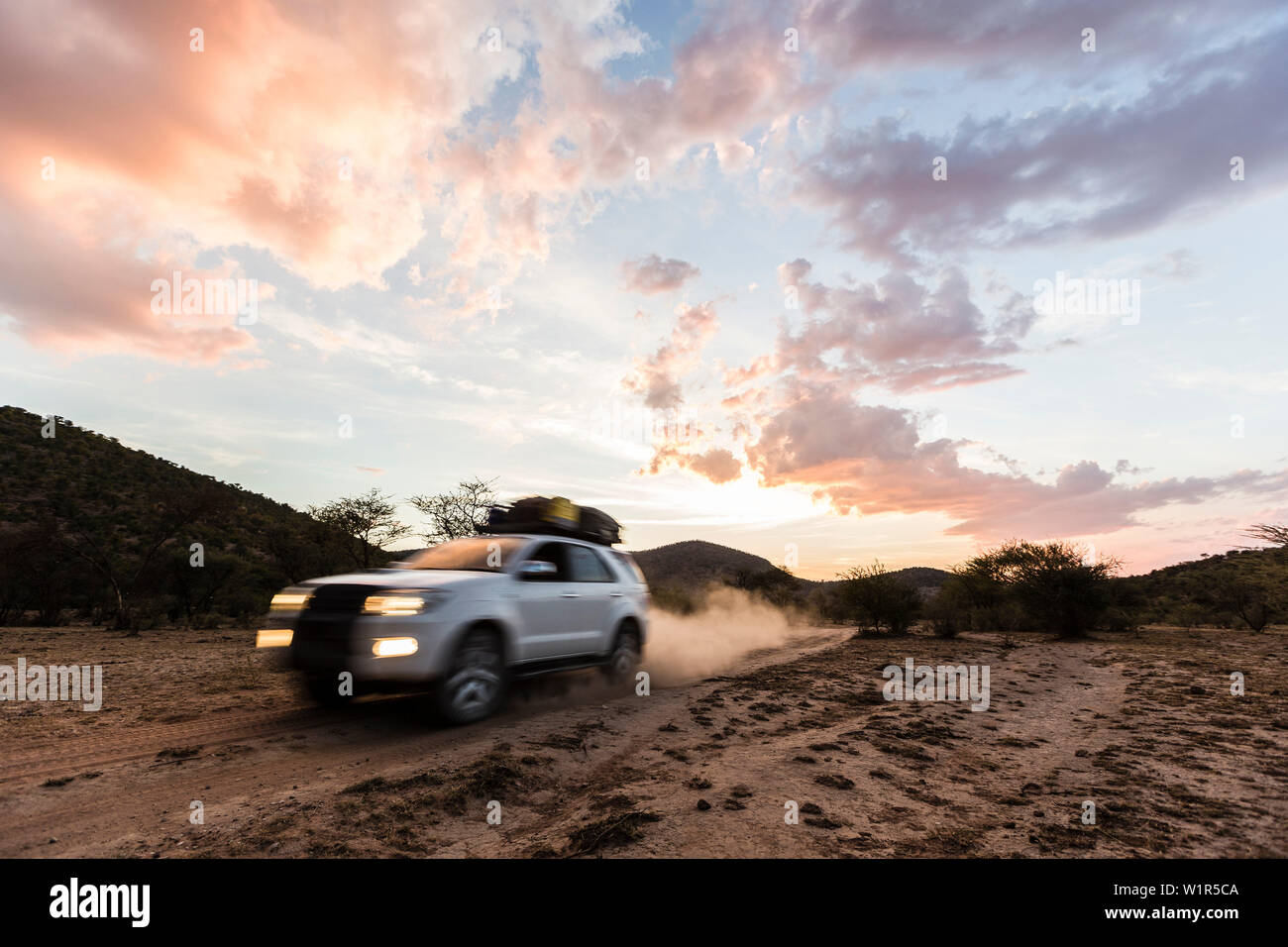 Véhicule tout terrain à la tombée de la nuit sur un chemin de terre dans le Damaraland, Namibie, Kunene Banque D'Images