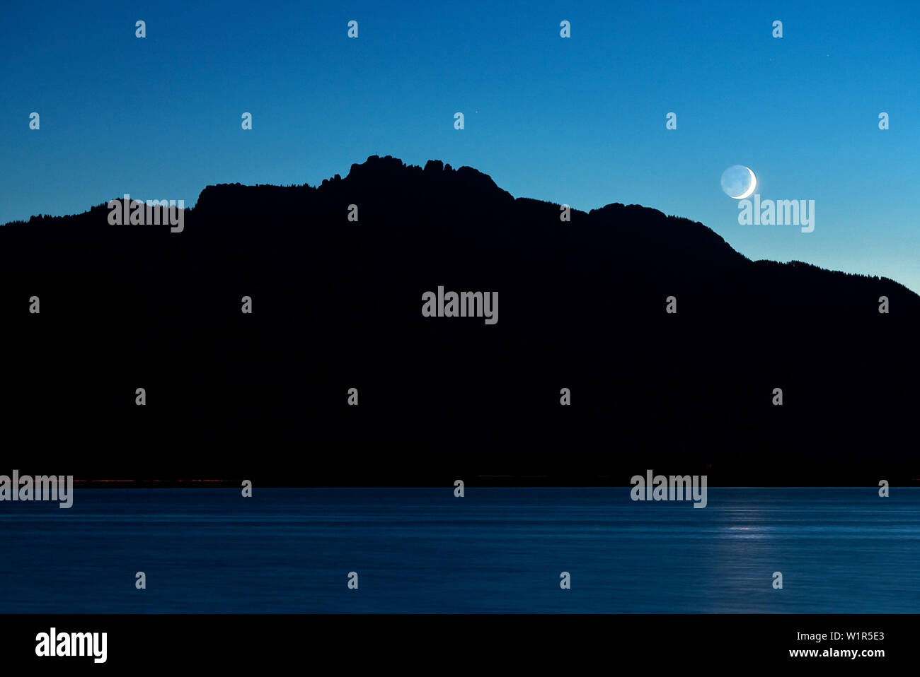 Feux arrière voiture comme baguettes lumineuses à l'avant du sur le lac de Chiemsee Kampenwand, la lune brille Banque D'Images