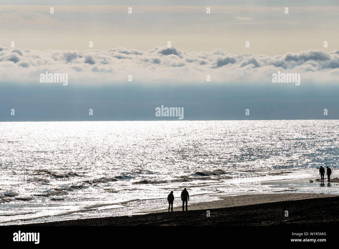 Beach walker après le lever du soleil, Wangerooge, Frise orientale, Basse-Saxe, Allemagne Banque D'Images