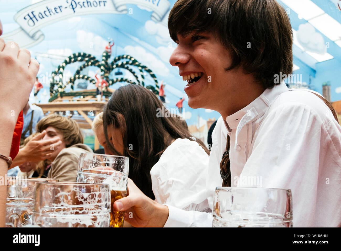 Young laughing man en tissu traditionnel dans la bière tente à l'Oktoberfest, Munich, Bavière, Allemagne Banque D'Images