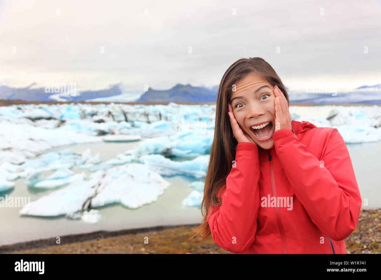 Heureux happy Woman at Glacier lagoon sur l'Islande faire drôle de visage d'expression. Happy tourist femme par le lac glaciaire Jökulsárlón dans un beau paysage de la nature islandaise avec des icebergs. Banque D'Images