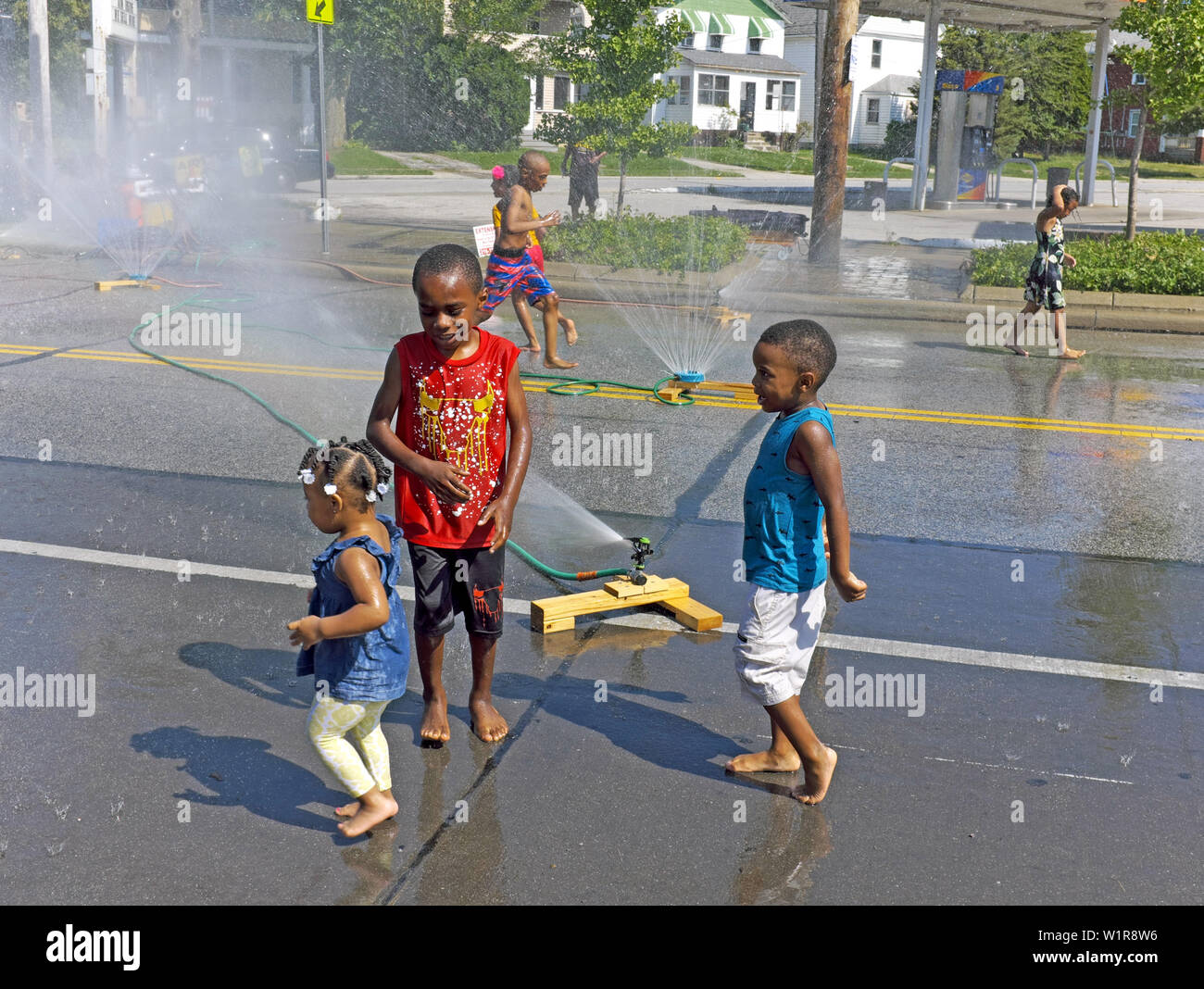 Les enfants se rafraîchir dans la rue sous aspersion d'eau mis en place pour battre la chaleur oppressante de l'été à Cleveland, Ohio, USA. Banque D'Images