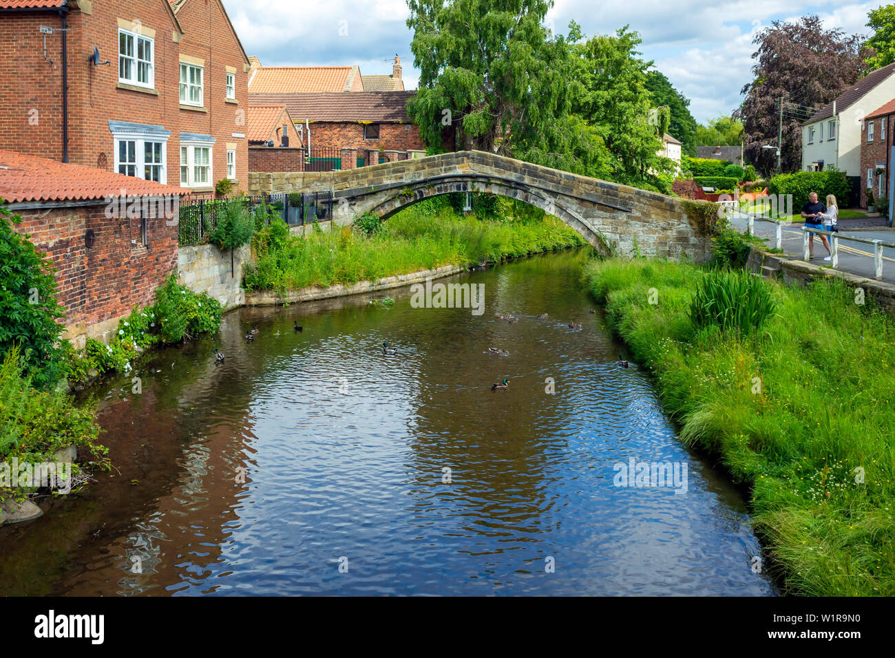 L'homme et la femme à discuter par le 17C pack horse pont sur la rivière Leven Shérif devient dans le Yorkshire du Nord, sur l'ancienne route packhorse de Durham à York Banque D'Images