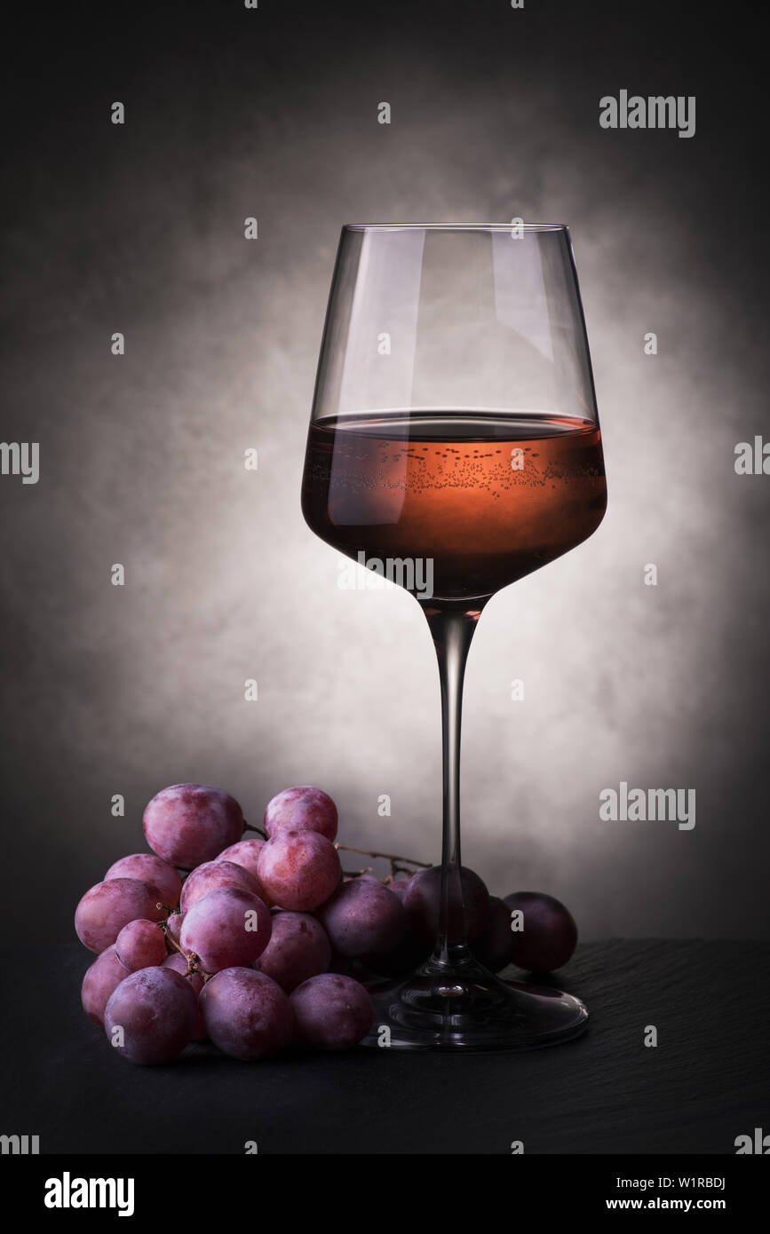 Nature morte avec verre de vin rose et grappe de raisins Banque D'Images
