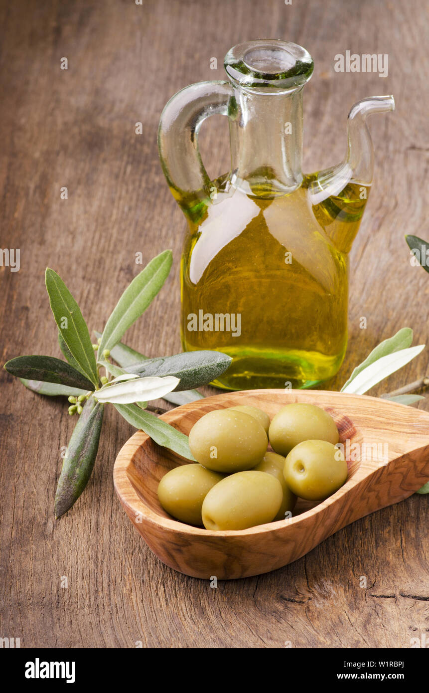 L'huile d'olive extra vierge dans une salière de verre et bol d'olives vertes Banque D'Images