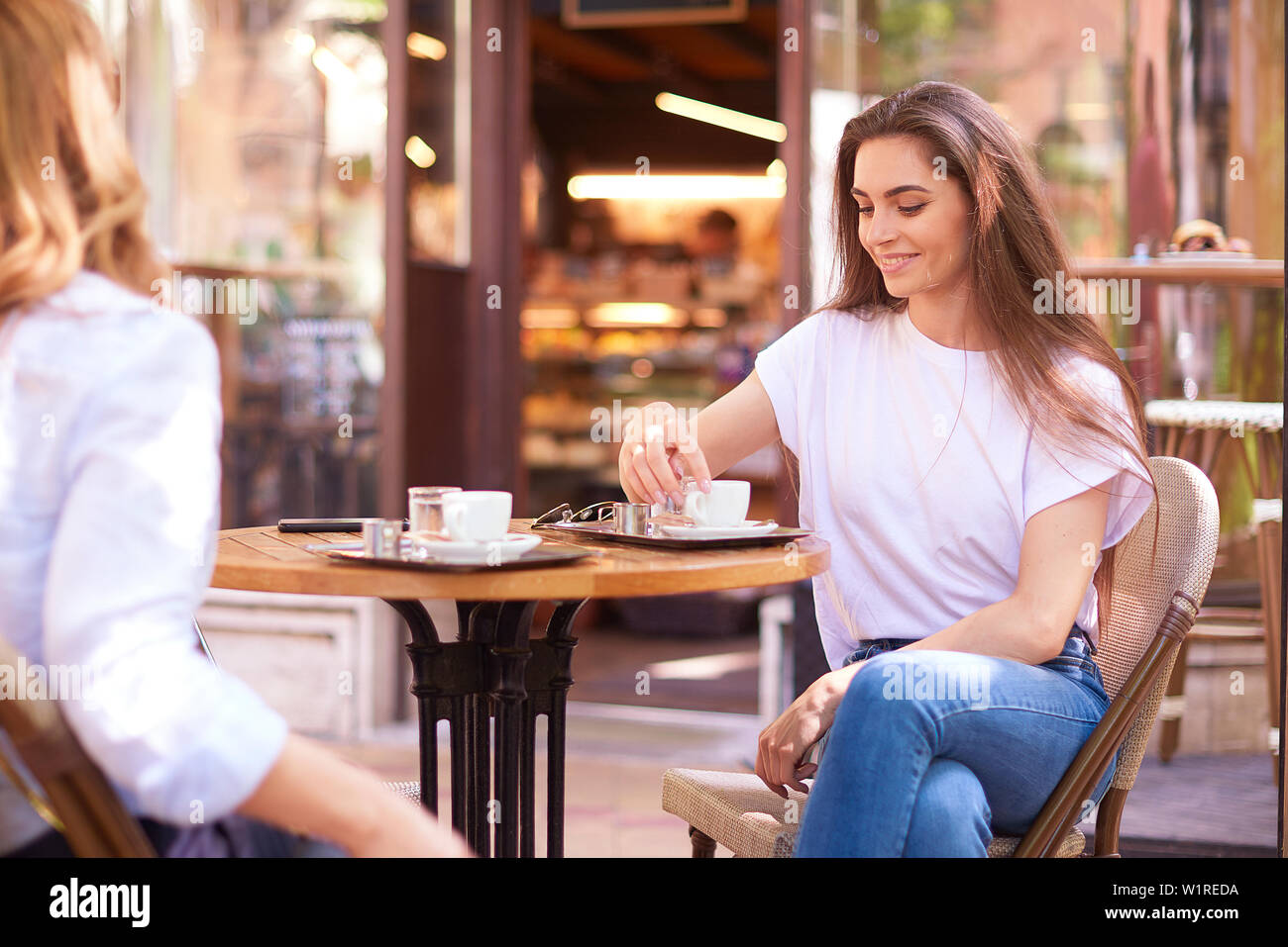 Shot of female friends talking in cafe assis à un bureau et le café et un croissant. Banque D'Images