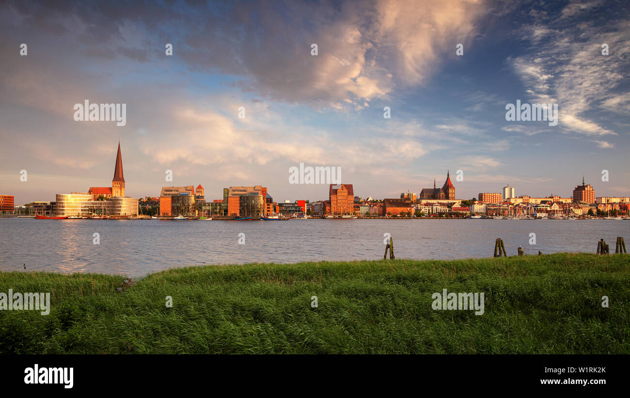 Rostock, Allemagne. Image panoramique de la ville de Rostock au bord de la rivière avec l'église Saint-Pierre pendant le coucher du soleil d'été. Banque D'Images