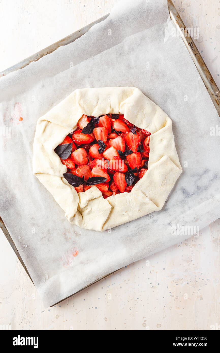 Gâteau aux fraises maison ouvrir de gallet avec basilic pourpre et sauce balsamique avant cuisson sur un pan de métal léger. Vue de dessus Banque D'Images