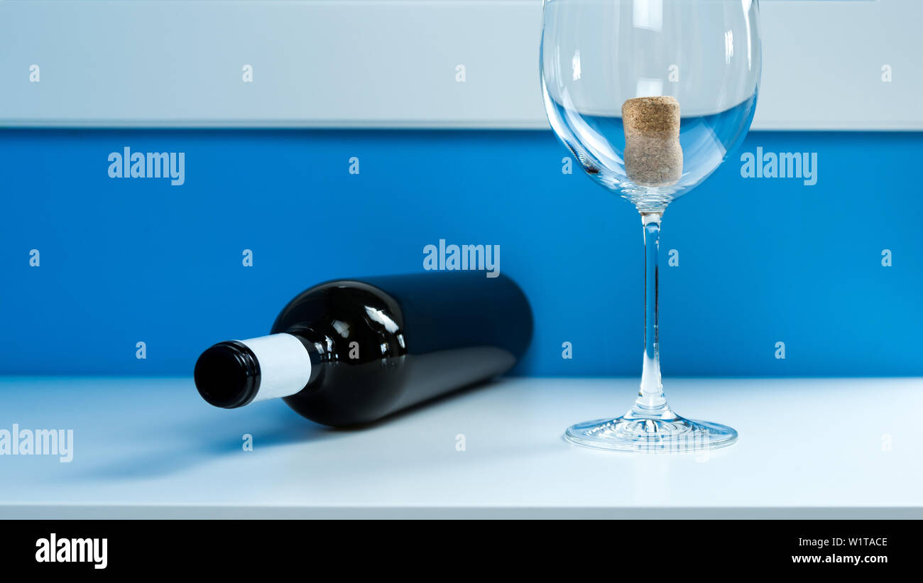 Verre de vin vide sur un tableau blanc à côté d'une bouteille de vin en verre foncé vide. L'intérieur du liège Banque D'Images