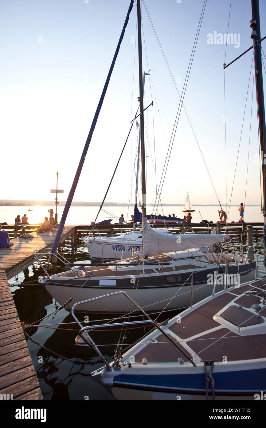 Les gens sur une jetée au coucher du soleil au lac Ammersee, Bavaria, Germany, Europe Banque D'Images