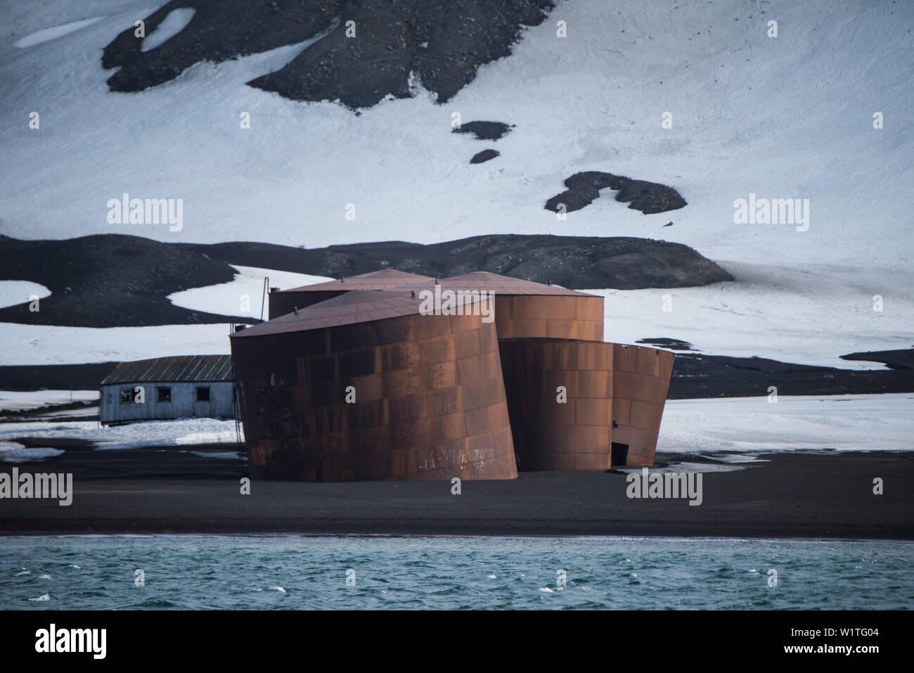 Réservoirs de stockage énorme bâtiment décrépi un nain dans l'arrière-plan, du témoin de l'histoire de la chasse ici, l'Île Déception, Isla Shetland du Sud Banque D'Images
