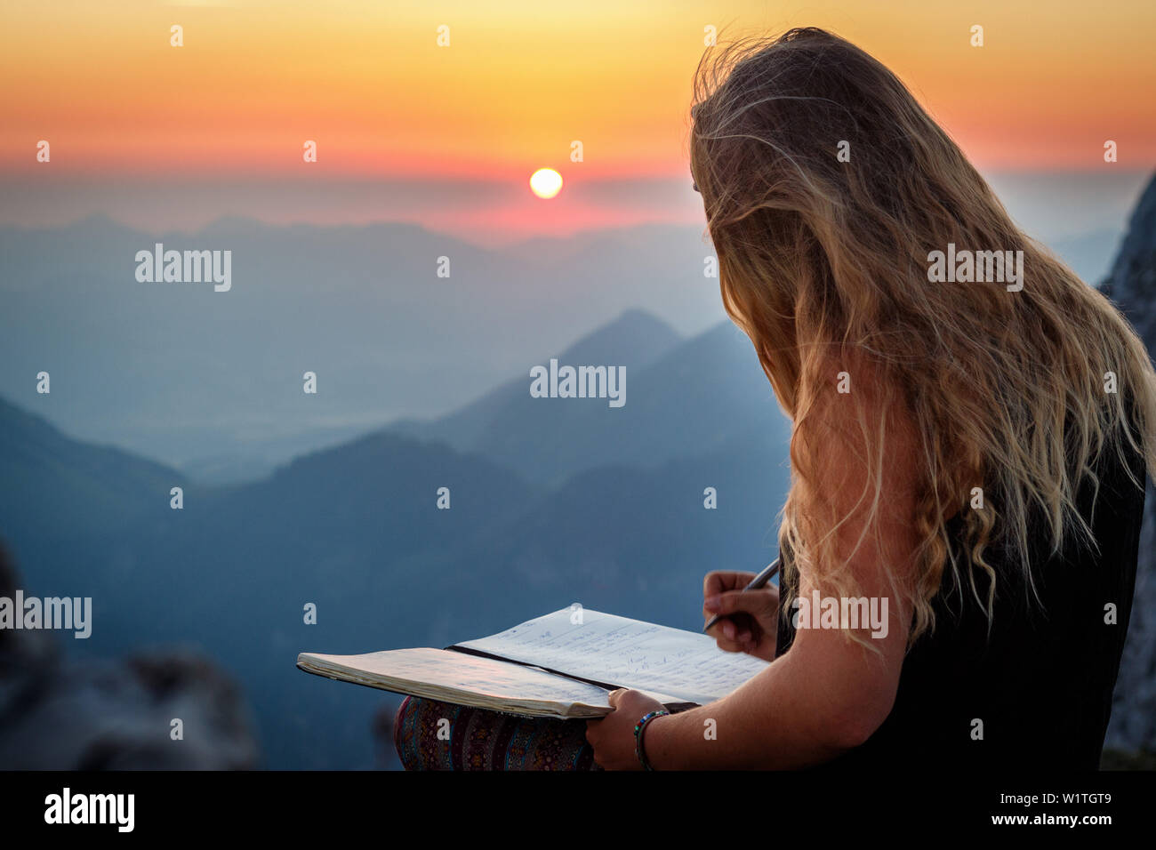 Jeune femme au sommet, écrit dans un livre, Scheffauer, Wilder Kaiser, Tyrol, Autriche Banque D'Images