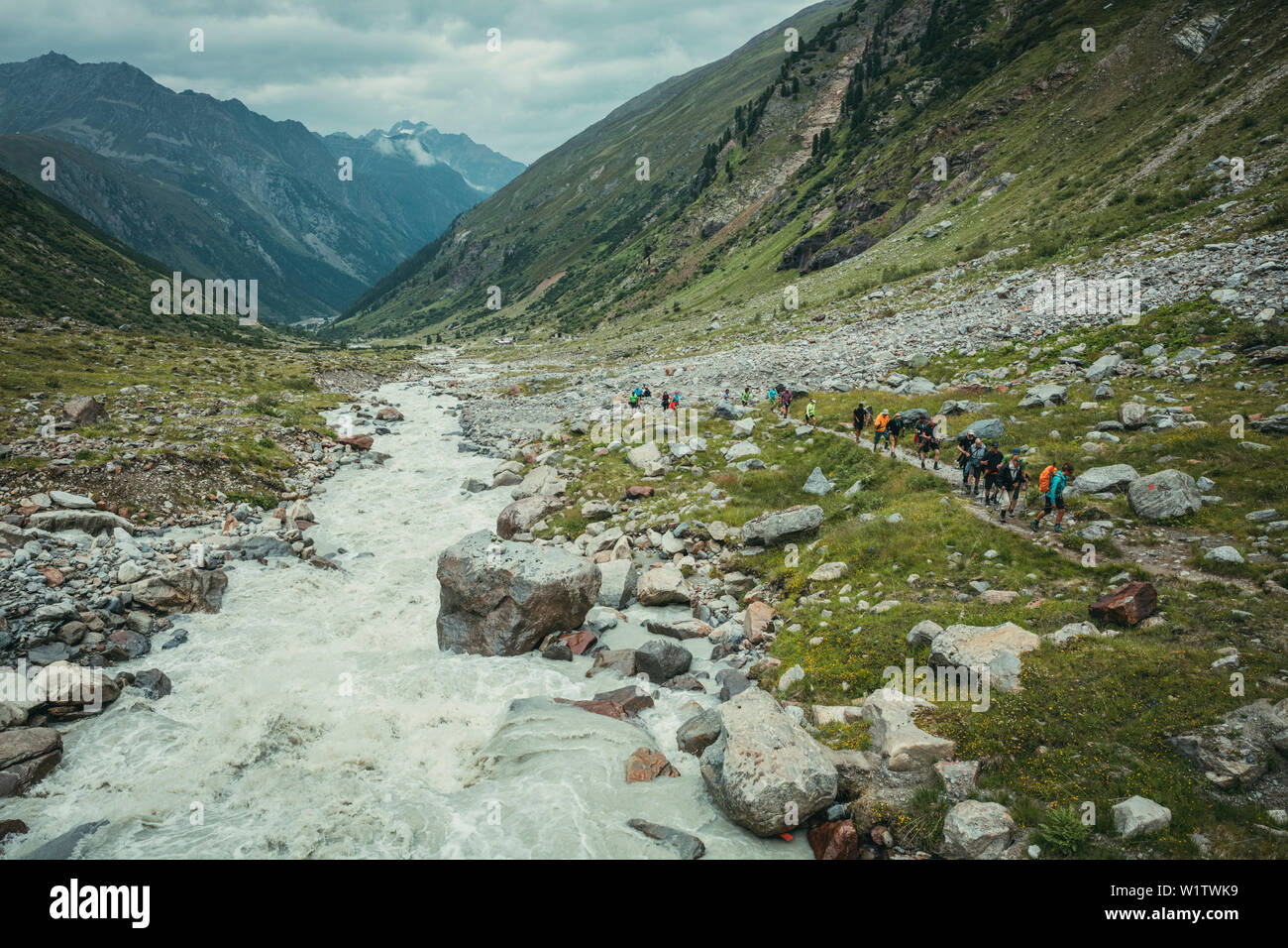 Groupe de randonnée sur un sentier de grande randonnée pédestre à côté d'un ruisseau de montagne, E5, Alpenüberquerung, 4e étape, Skihütte Zams, Lacheralm,Pitztal, Wenns, Gletsc Banque D'Images