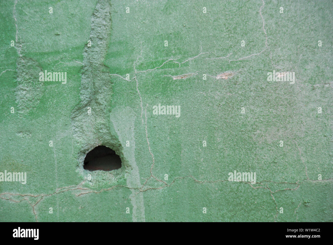 Joli mur détérioré qui a un trou dans sa surface et est peint en vert clair Banque D'Images