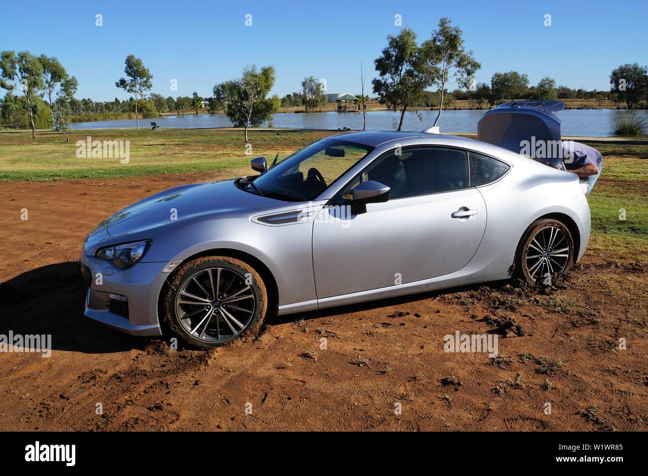 Voiture de sport de l'argent bloqué sur un sol meuble dans un paysage pittoresque Banque D'Images