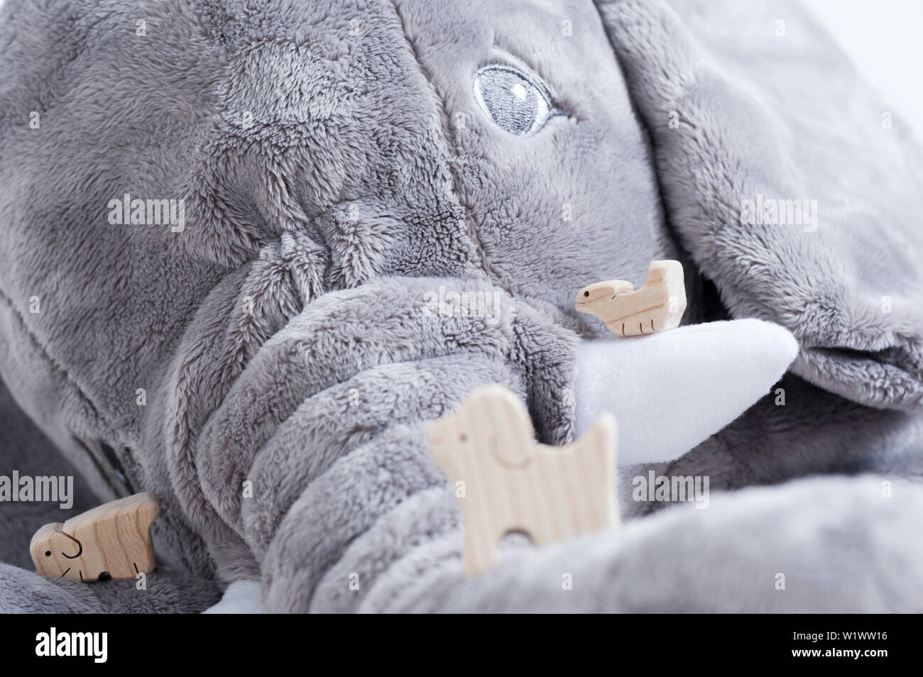 Jouet en bois mignon animaux sur la planche en bois blanc avec poupée éléphant géant dans l'arrière-plan, petits jouets et profondeur de champ Banque D'Images