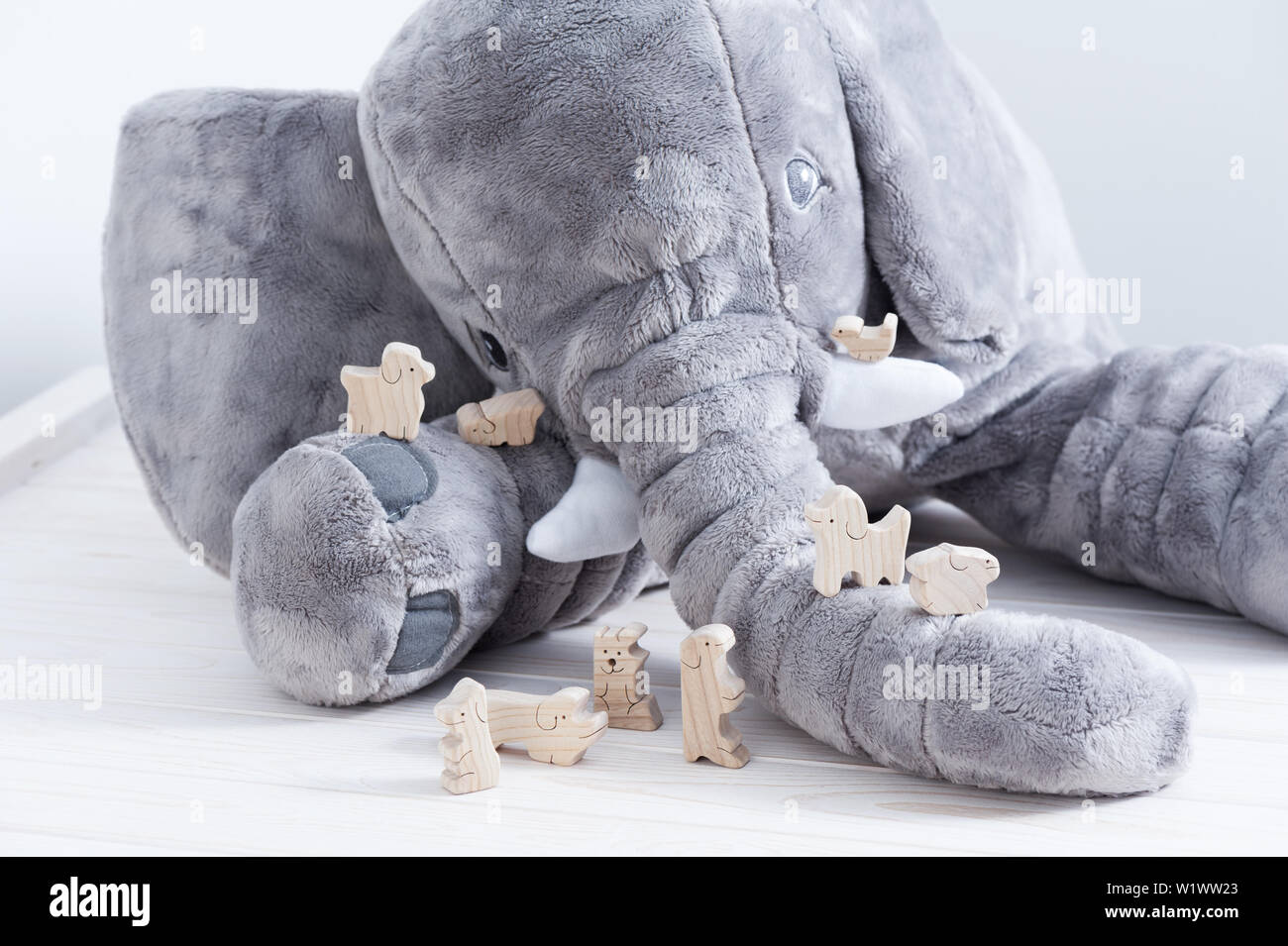 Jouet en bois mignon animaux sur la planche en bois blanc avec poupée éléphant géant dans l'arrière-plan Banque D'Images