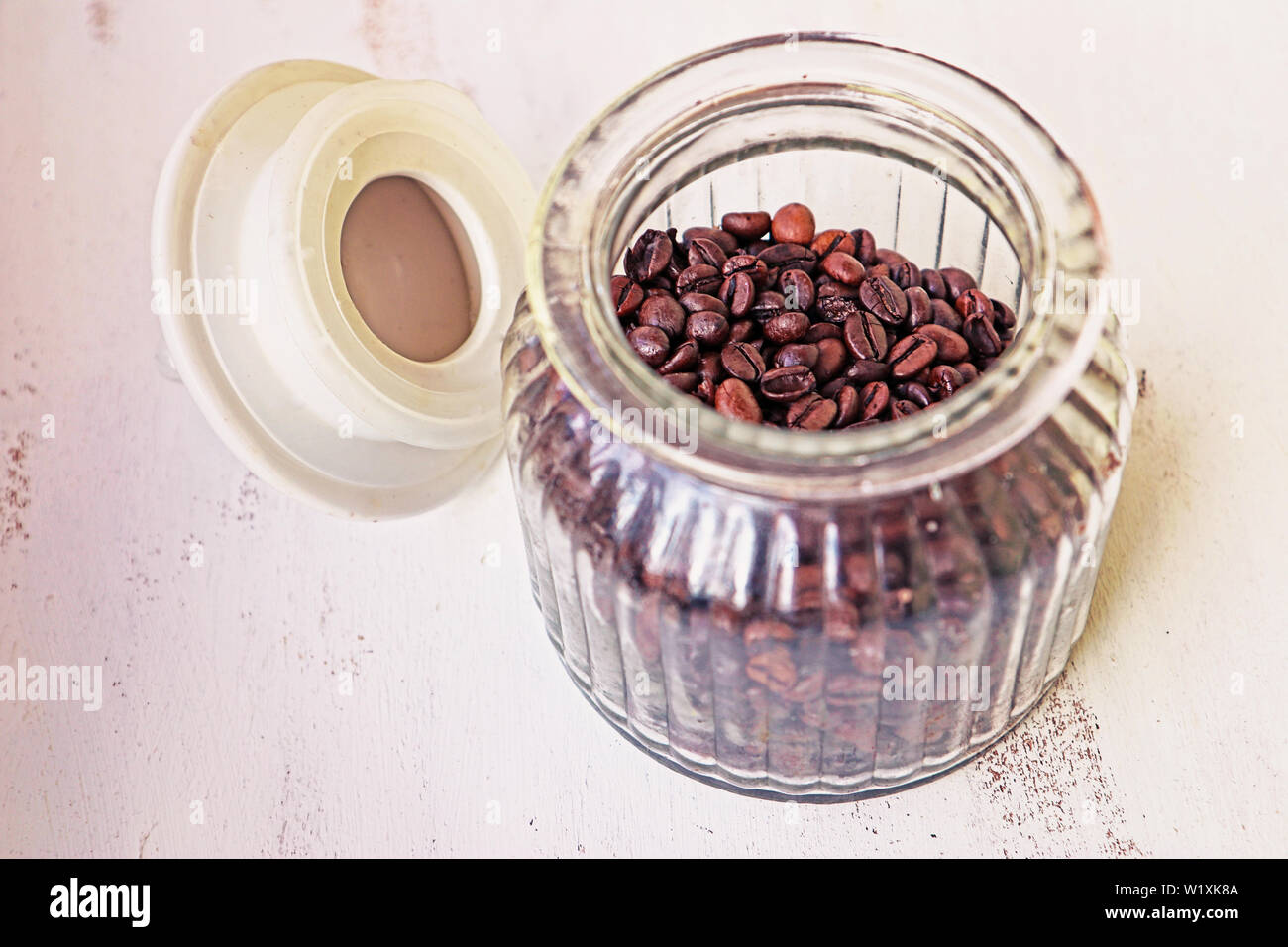 Les grains de café torréfié en vase en verre sur la table de cuisine Banque D'Images