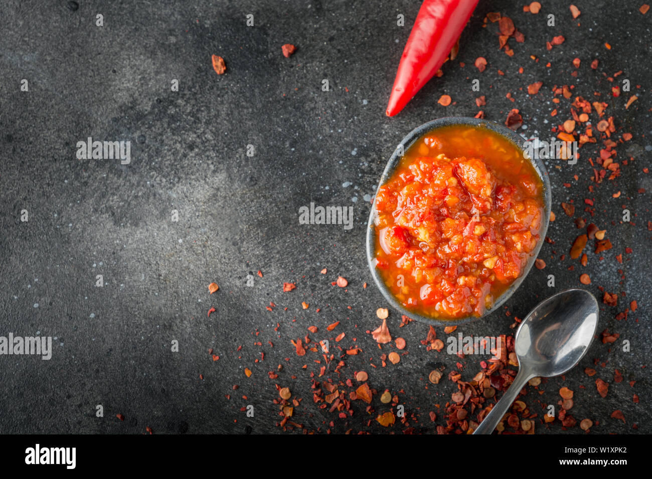 Adjika traditionnel piment pâte sauce harissa sur noir. La Tunisie, géorgienne et arabes. Orientation horizontale. Vue d'en haut. L'espace pour te Banque D'Images