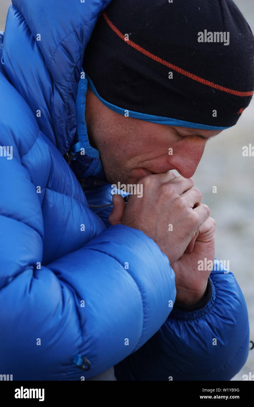 Gros plan d'une alpiniste pensif et concentré dans un épais Down jacket perdu dans ses pensées et à l'avant Banque D'Images Gros plan d'une alpiniste pensif et concentré dans un épais Down jacket perdu dans ses pensées et à l'avant Banque D'Images