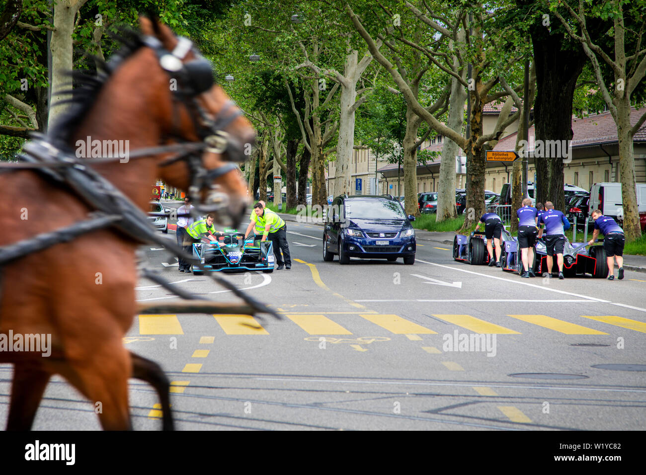 La vitesse d'un cheval caddy passé tout en membres d'équipage pousse l'un de l'HWA Formule E voitures de la pitlane retour au garage de l'avant de la course de Formule E ABB à Berne. Banque D'Images
