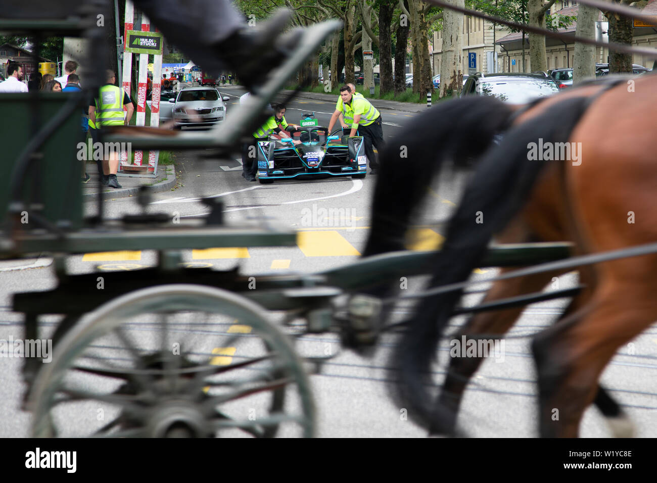 La vitesse d'un cheval caddy passé tout en membres d'équipage pousse l'un de l'HWA Formule E voitures de la pitlane retour au garage de l'avant de la course de Formule E ABB à Berne. Banque D'Images