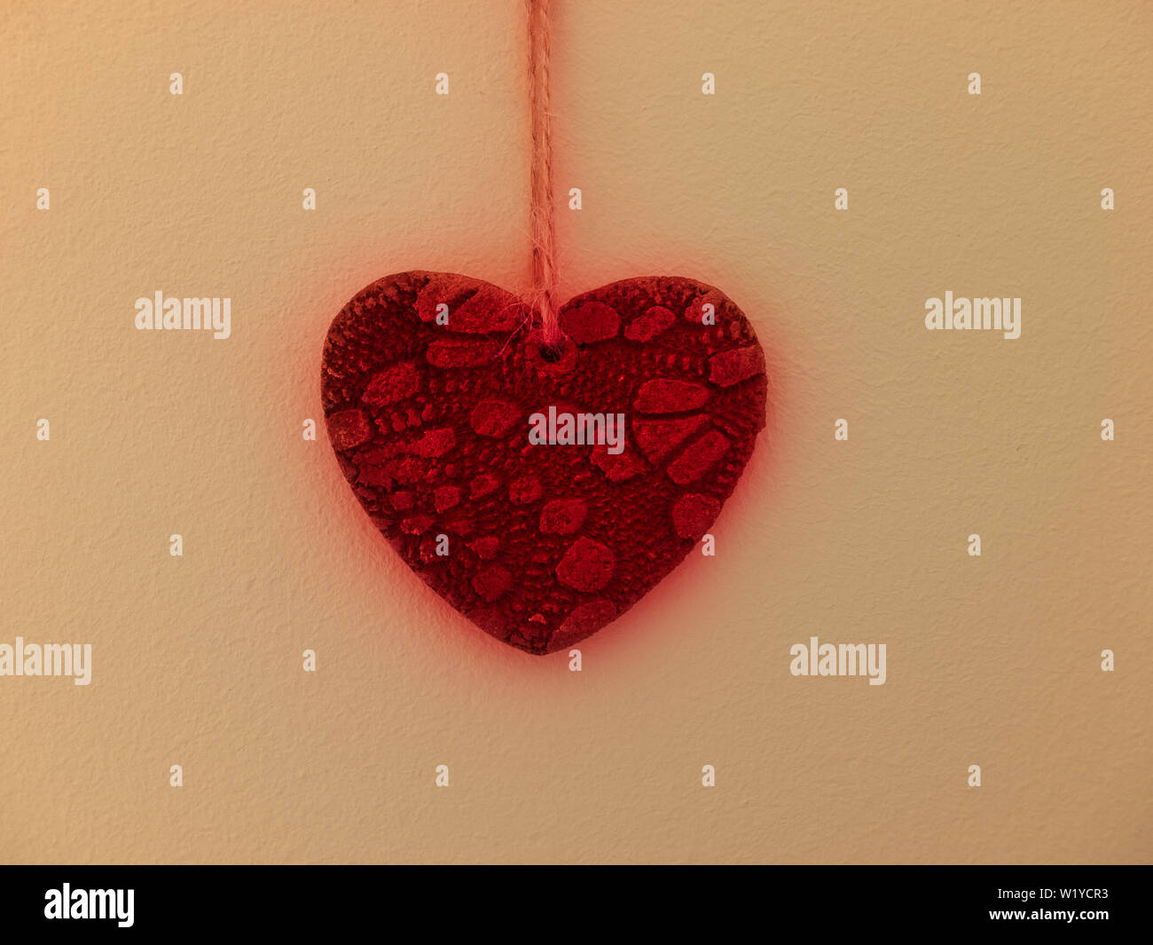 Pierre rougeoyants rouges coeur accroché au mur jaune couverts wi Banque D'Images