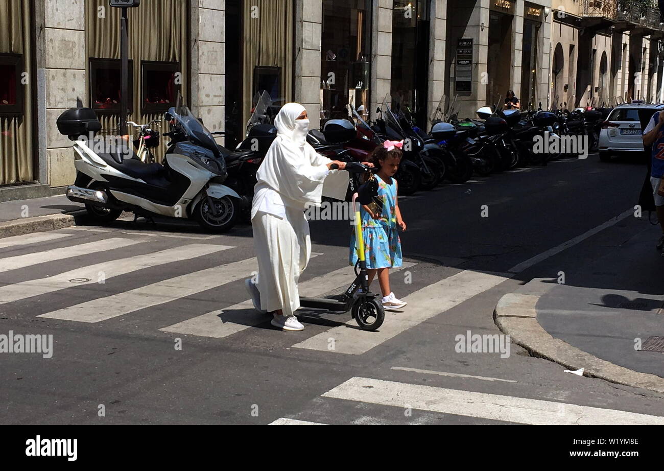 Milan, femme musulmane sur scooter électrique dans le centre une femme musulmane, portait un burqa, circule dans la Via Montenapoleone à bord d'un scooter électrique, apportant avec elle une petite fille. Banque D'Images