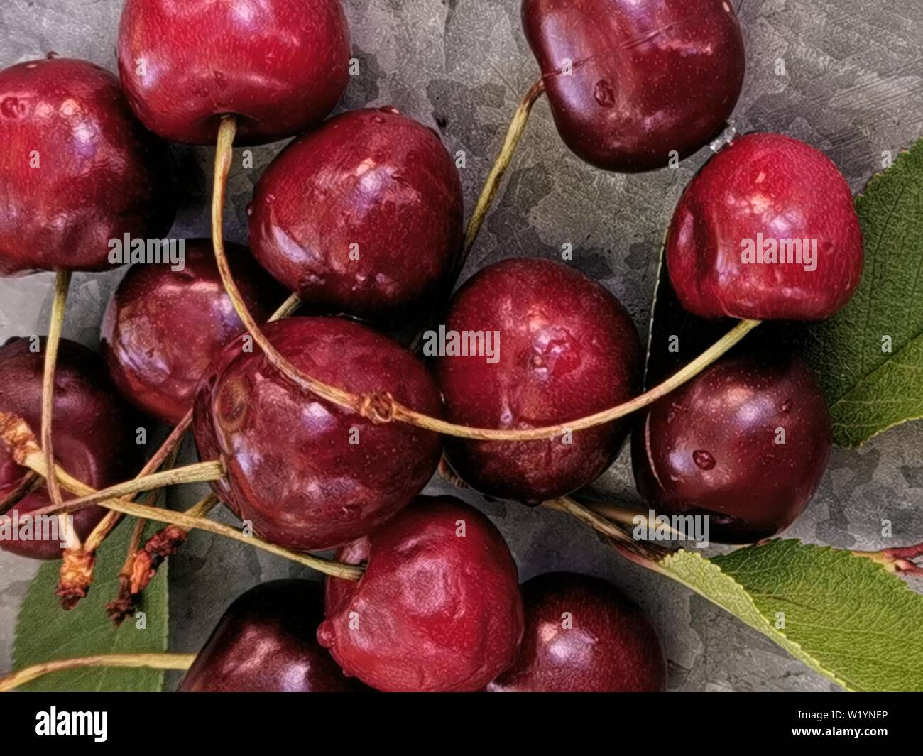 Belle cerise sur le tableau et sur la soucoupe. Des cerises et des noyaux de cerise, de puits sur une plaque Banque D'Images