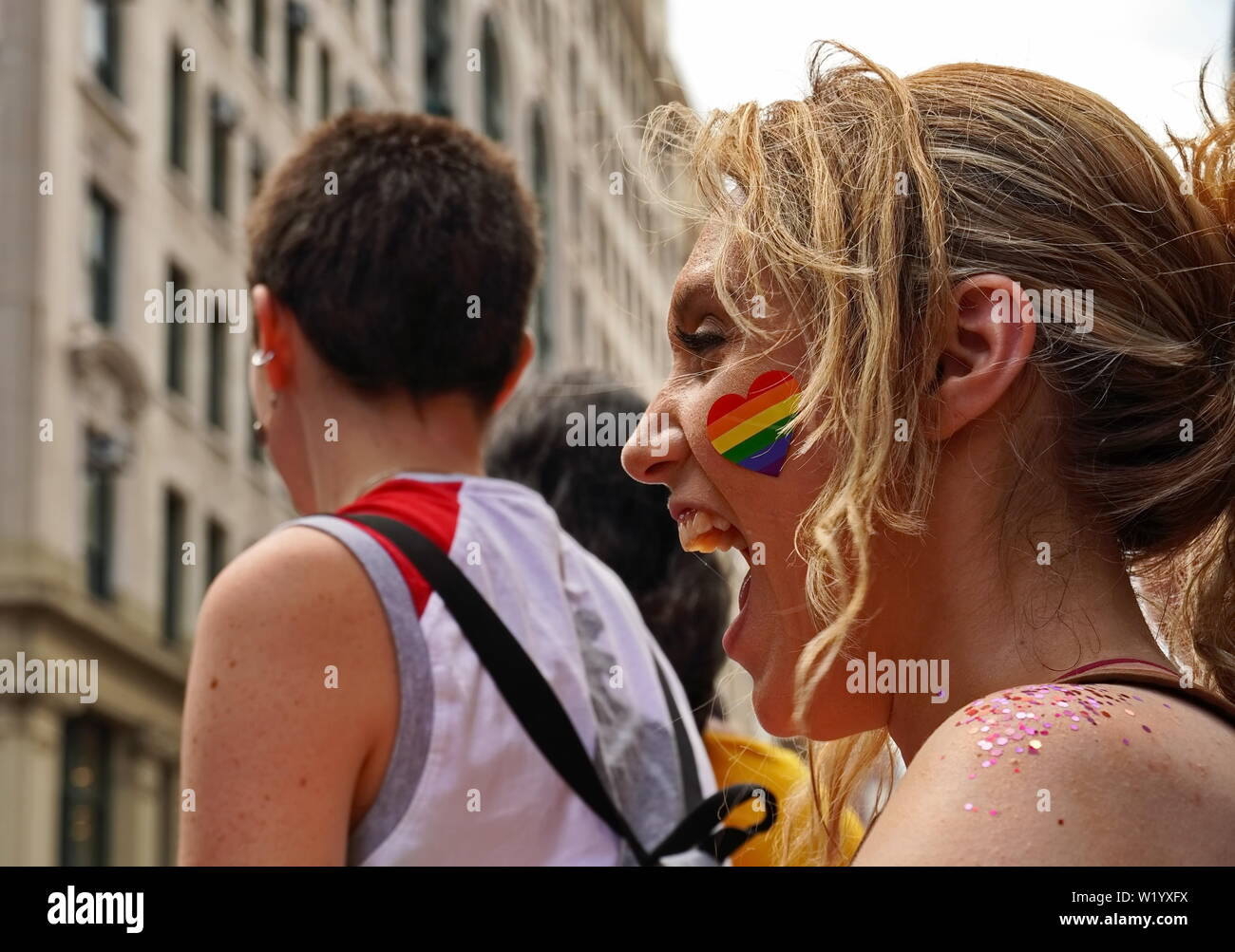 New York City, NY / USA - 20 juin 2019 : Jeune femme avec un coeur rainbow sticker montre un sourire joyeux Banque D'Images