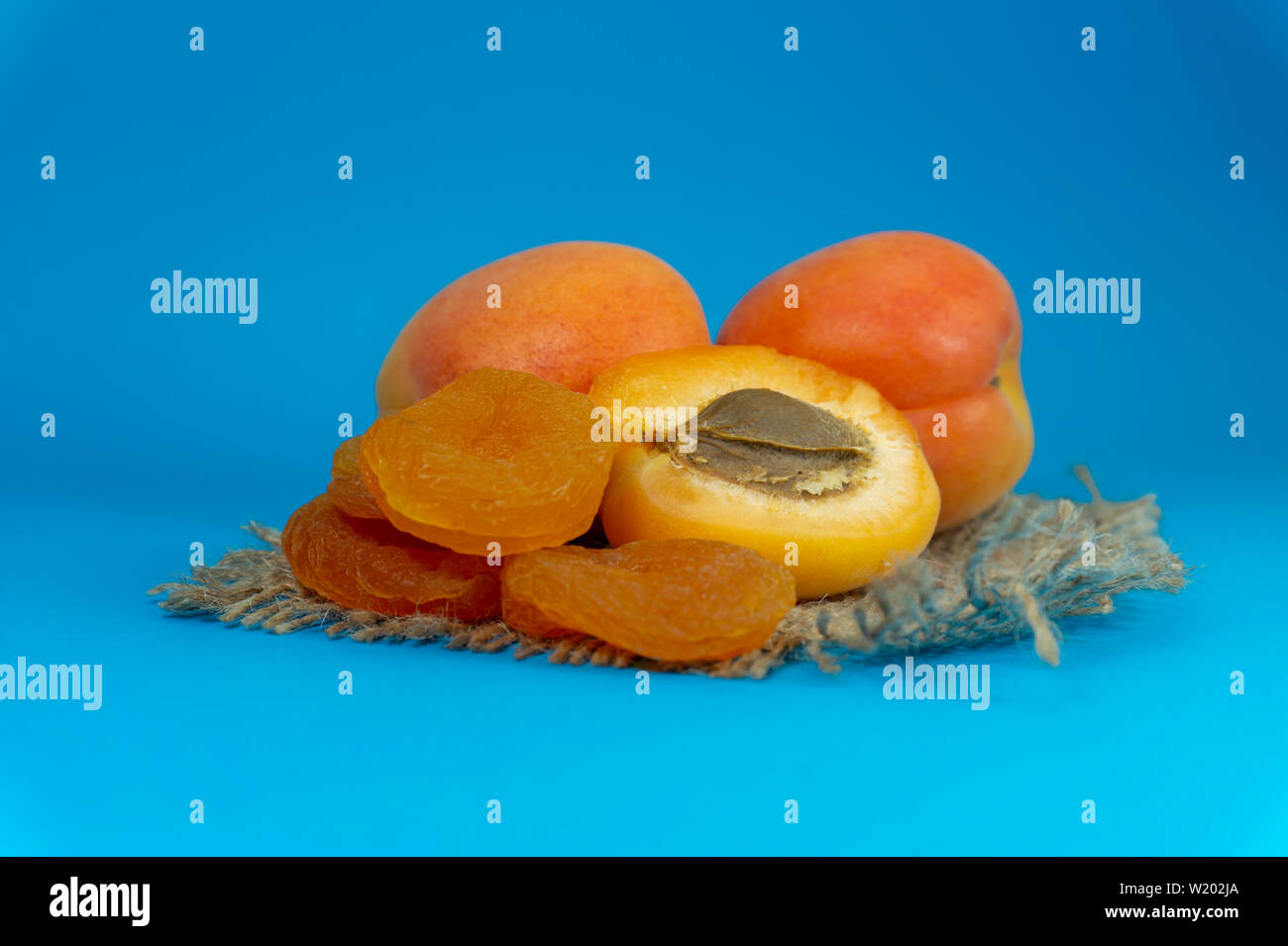 Abricots séchés et poisson frais entier et tranchées abricots coupés en deux sur un carré de toile de jute rustique dans une vue en gros plan Banque D'Images