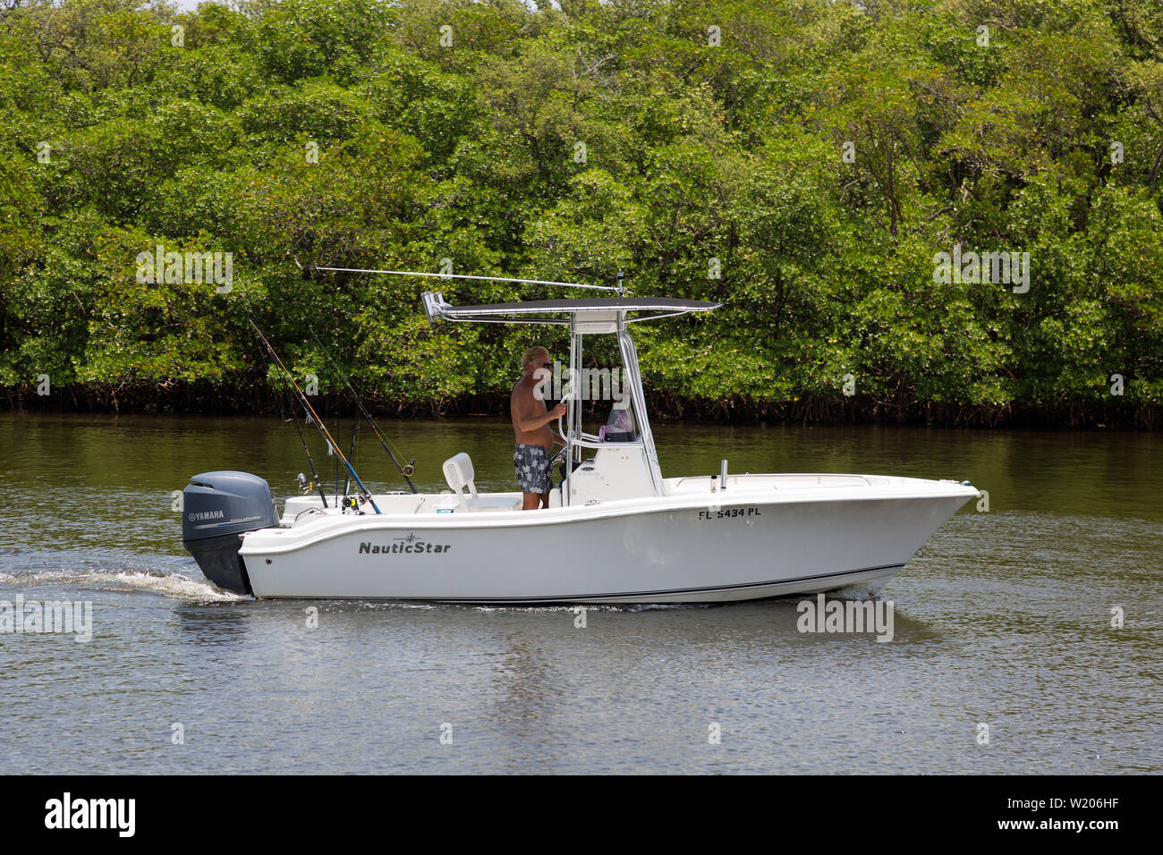 Un pêcheur pilote son bateau de pêche NauticStar à travers les eaux calmes de la voie navigable Intercoastal entre Boynton Beach et Ocean Ridge, Floride, États-Unis Banque D'Images