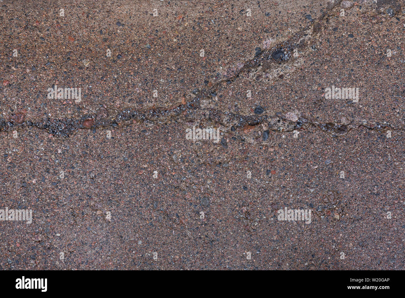 Close-up of a wet, érodés et béton fissuré avec surface sentier cailloux (ou pebblecrete ou agrégat) à l'extérieur, vue de dessus). Banque D'Images