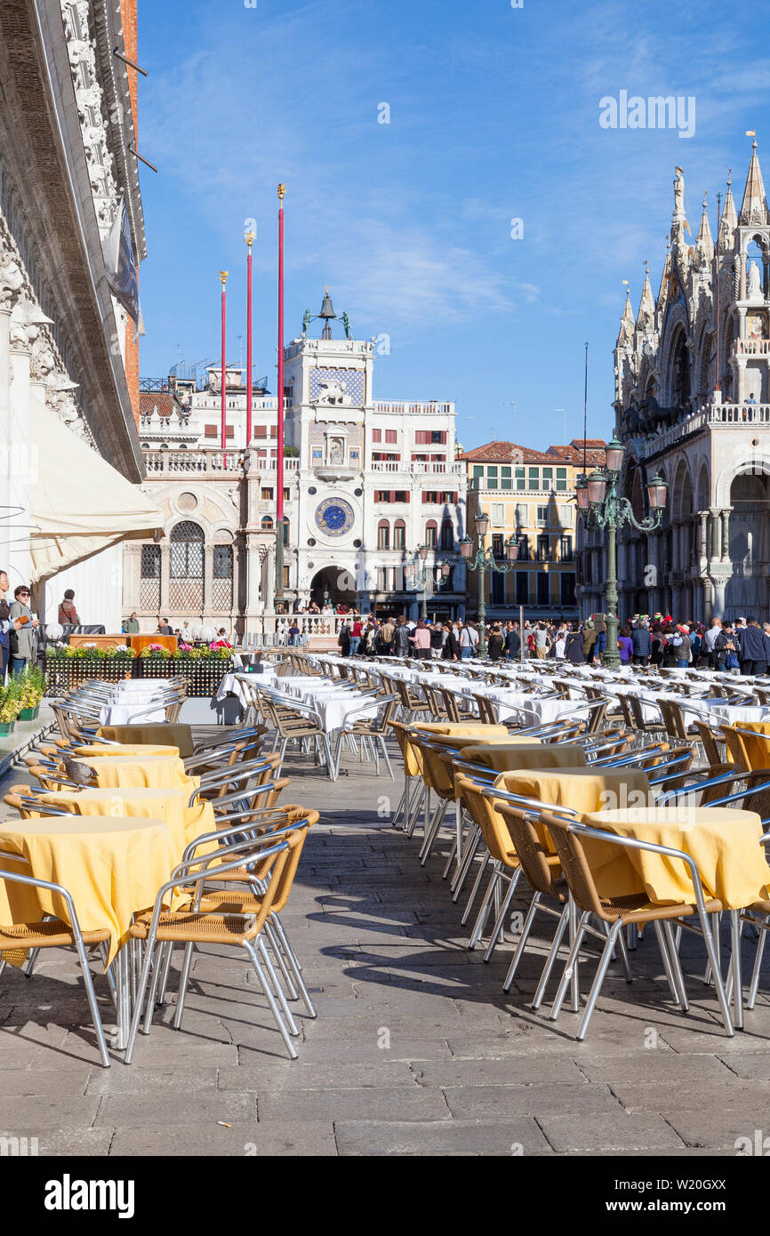 Tableaux mis prêt pour le déjeuner dans la Piazetta San Marco, Venise, Vénétie, Italie en vue de la tour de l'horloge et la basilique avec des foules de touristes sightse Banque D'Images