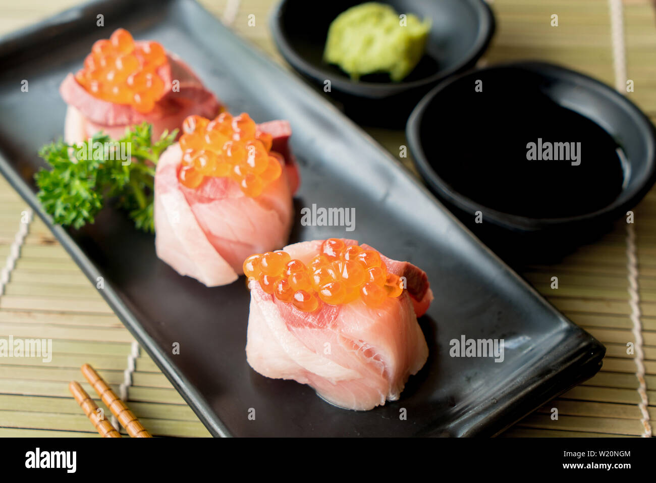 Oeufs de saumon sur Hamachi sushi sur la plaque noire avec la sauce japonaise et vert feuille décor, la nourriture Japonaise, Close up à sushi. Banque D'Images