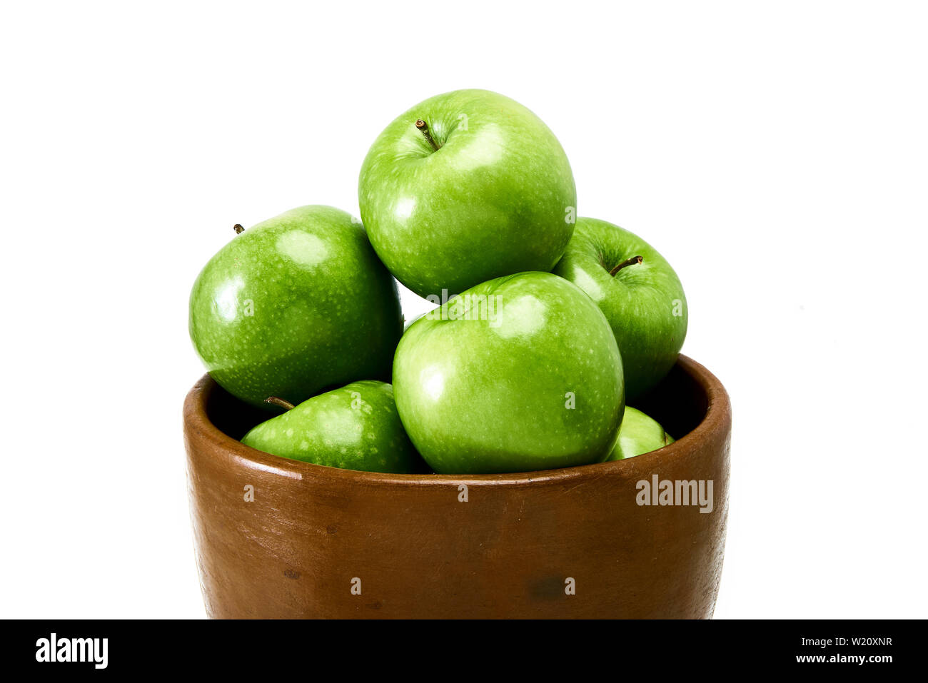 Un groupe de la cuisson des pommes Granny Smith verte dans un bol brun isolé sur un fond blanc. Banque D'Images