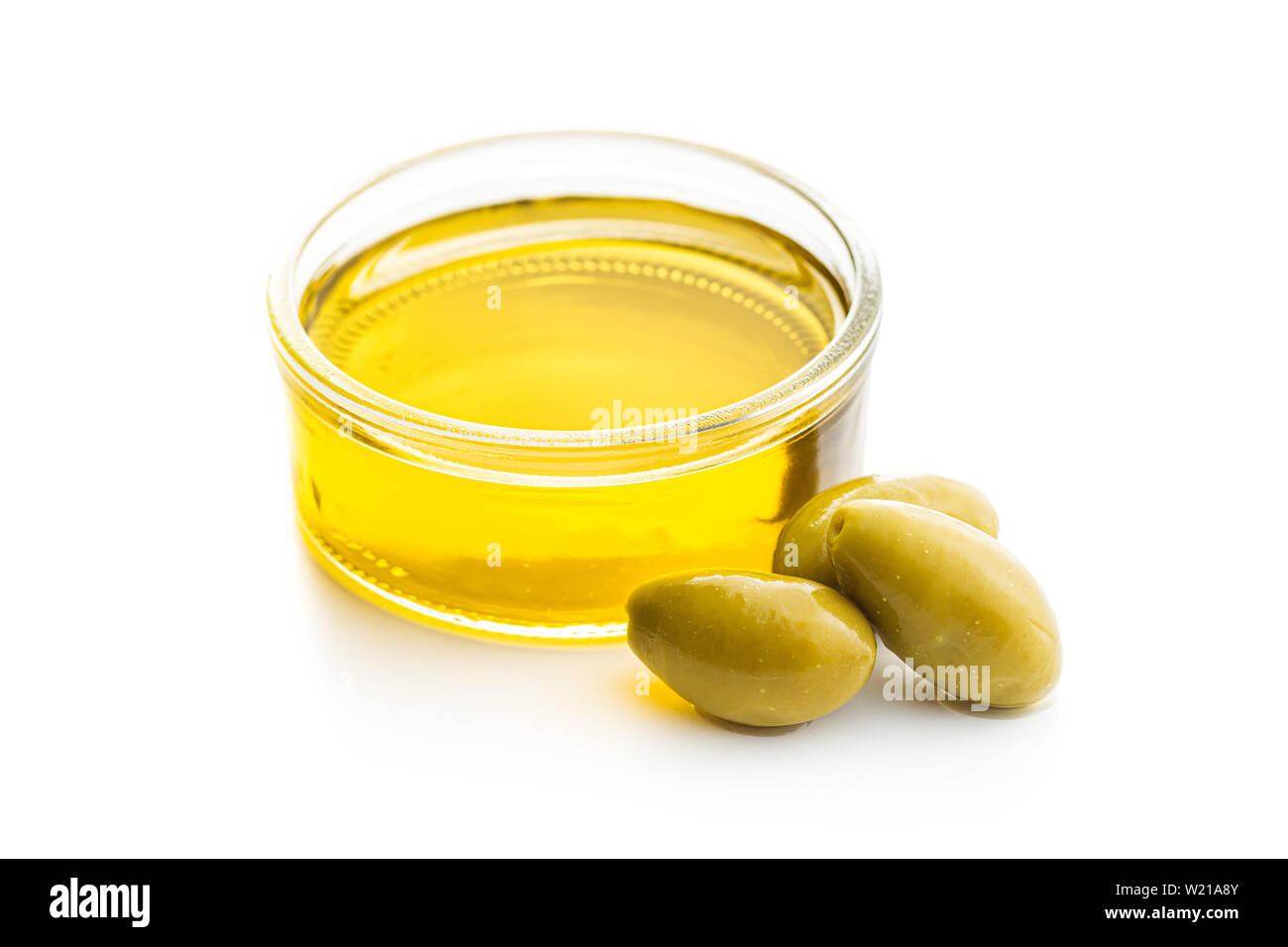 Green olives et huile d'olive dans un bol en verre isolé sur fond blanc. Banque D'Images