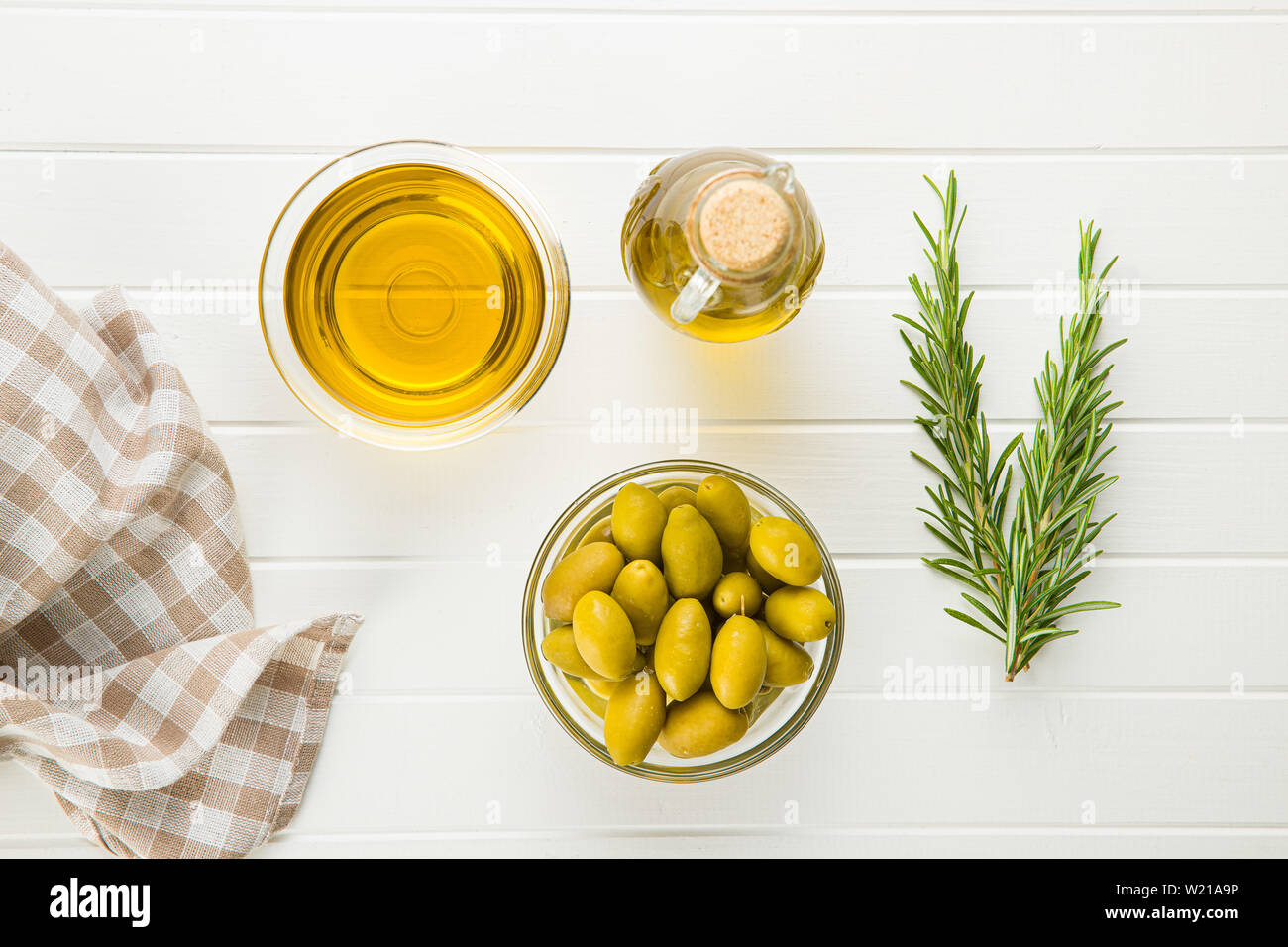 Green olives et huile d'olive dans un bol de verre sur la table blanche. L' affichage. Banque D'Images