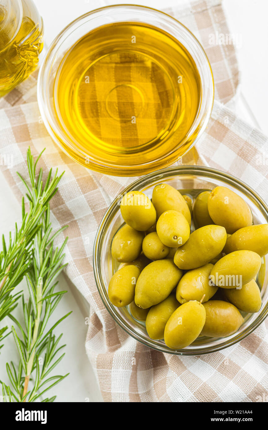 Green olives et huile d'olive dans un bol de verre sur une serviette à carreaux. L' affichage. Banque D'Images