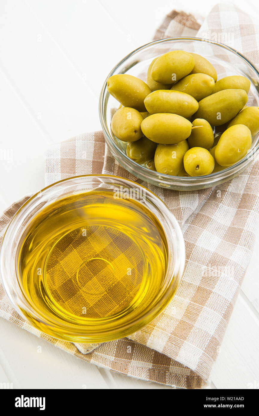 Green olives et huile d'olive dans un bol de verre sur une serviette à carreaux. Banque D'Images