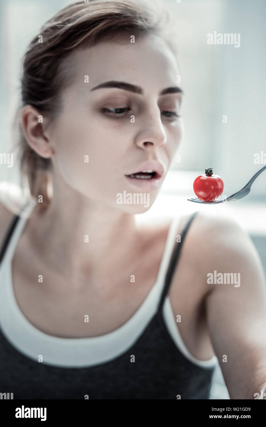 Accents lumineux. Frustrés girl holding fourche avec la tomate et rêver de la viande Banque D'Images